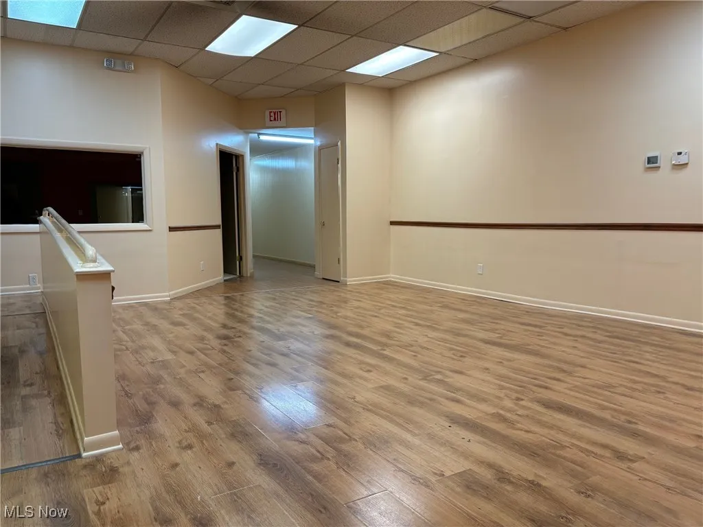 Finished room with a drop ceiling and hardwood / wood-style flooring
