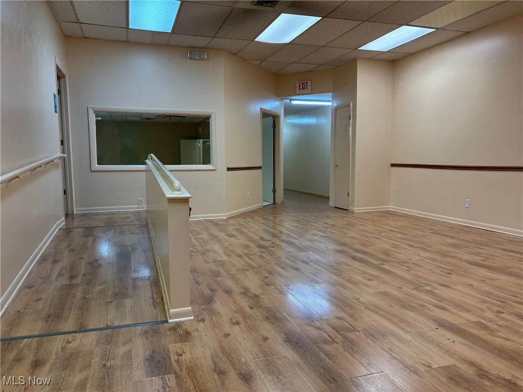 Empty room with a paneled ceiling and wood-type flooring