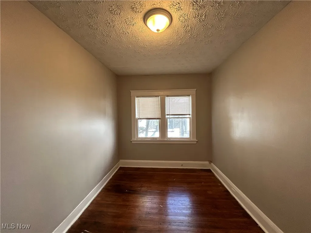 Spare room featuring a textured ceiling and dark hardwood / wood-style flooring