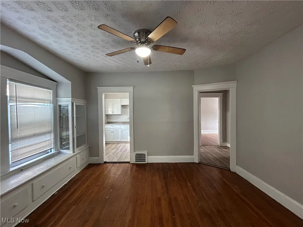 Unfurnished room featuring ceiling fan, a textured ceiling, and dark hardwood / wood-style floors