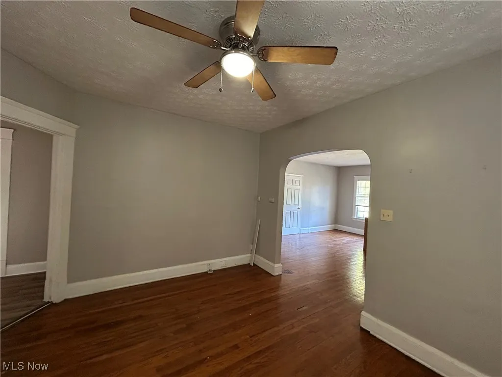 Unfurnished room featuring ceiling fan, a textured ceiling, and dark hardwood / wood-style flooring