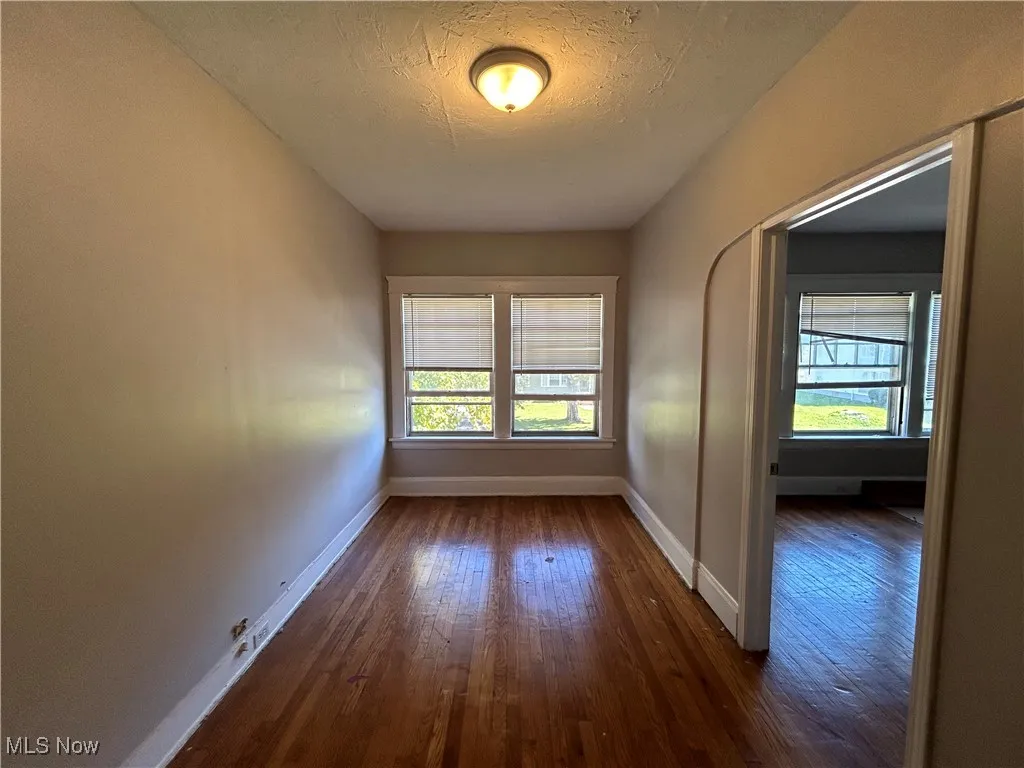 Empty room with a textured ceiling, plenty of natural light, and dark hardwood / wood-style flooring