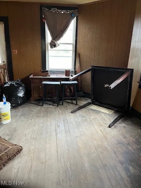 Misc room with light hardwood / wood-style floors and wood walls