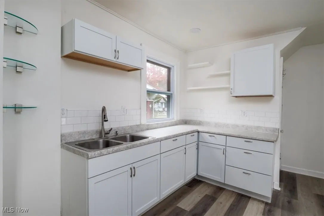 Kitchen featuring dark hardwood / wood-style flooring, tasteful backsplash, sink, and white cabinets