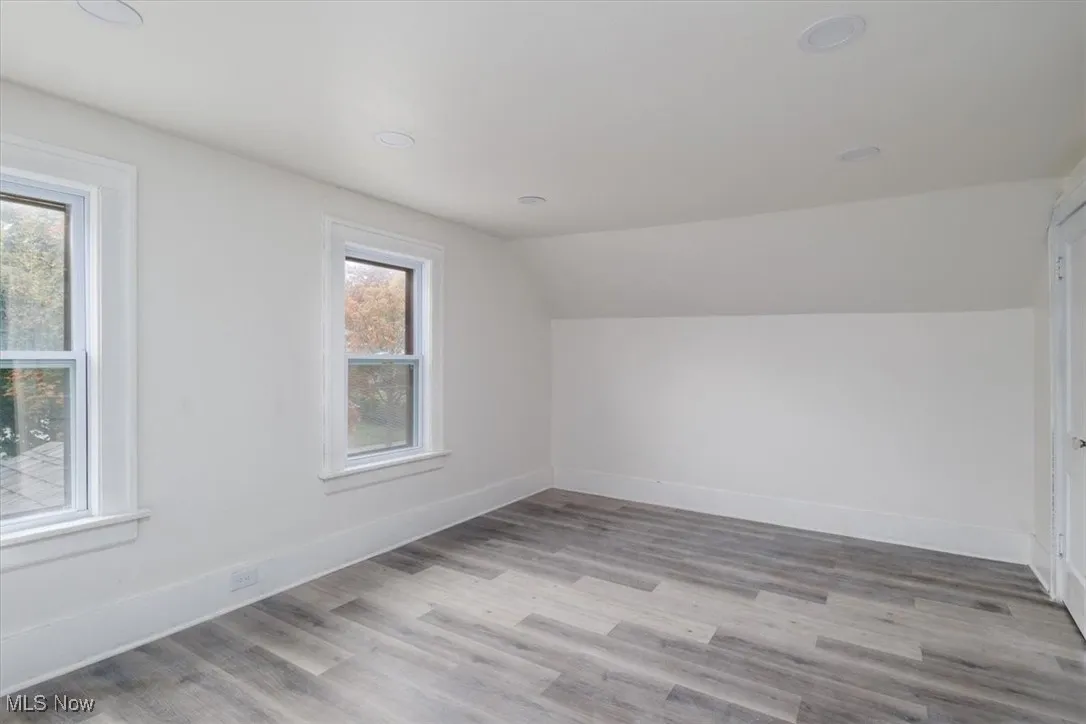 Additional living space with light hardwood / wood-style flooring, vaulted ceiling, and a wealth of natural light