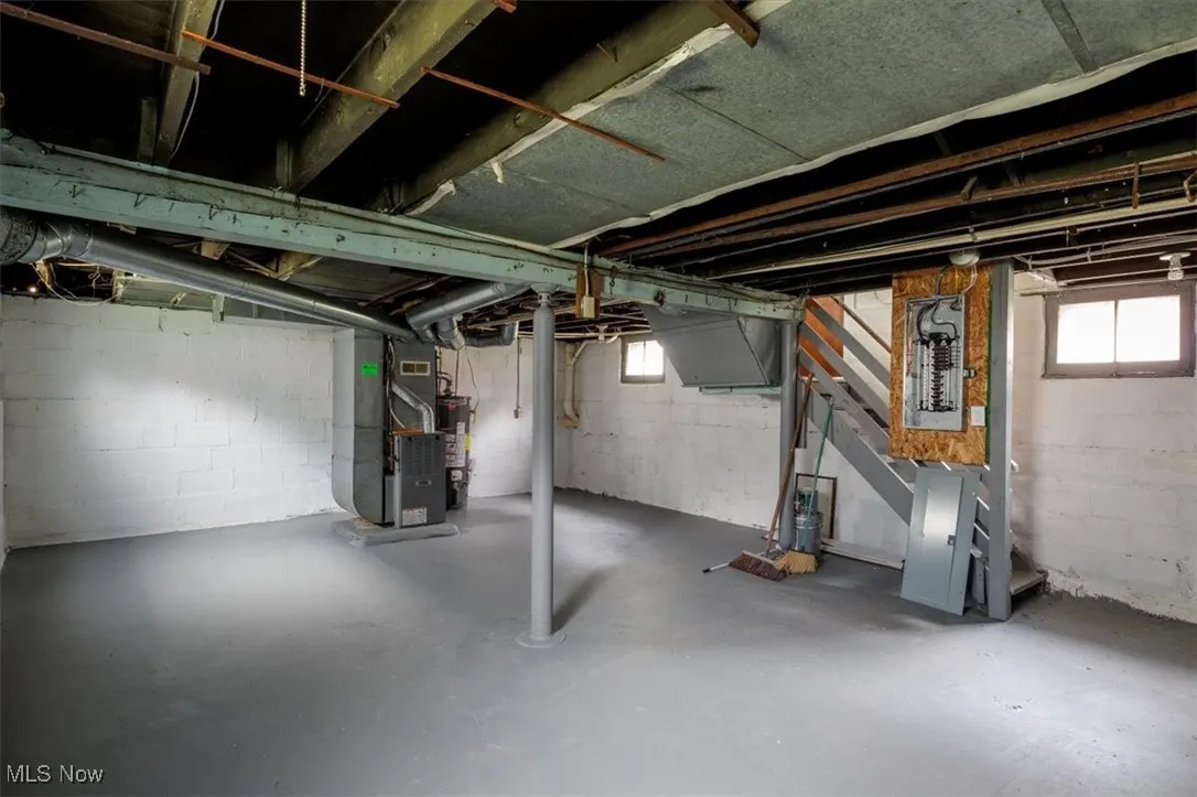 Basement with water heater, electric panel, and heating unit