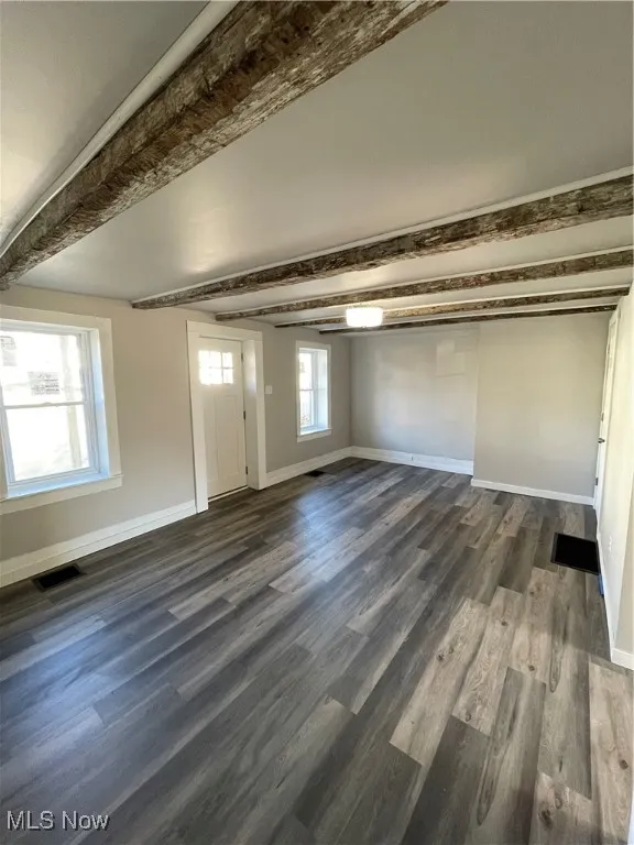 Unfurnished room with beamed ceiling and dark hardwood / wood-style floors
