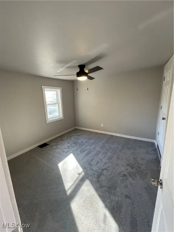 Carpeted empty room featuring ceiling fan