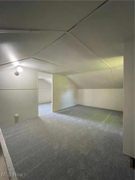 Additional living space with vaulted ceiling and carpet floors