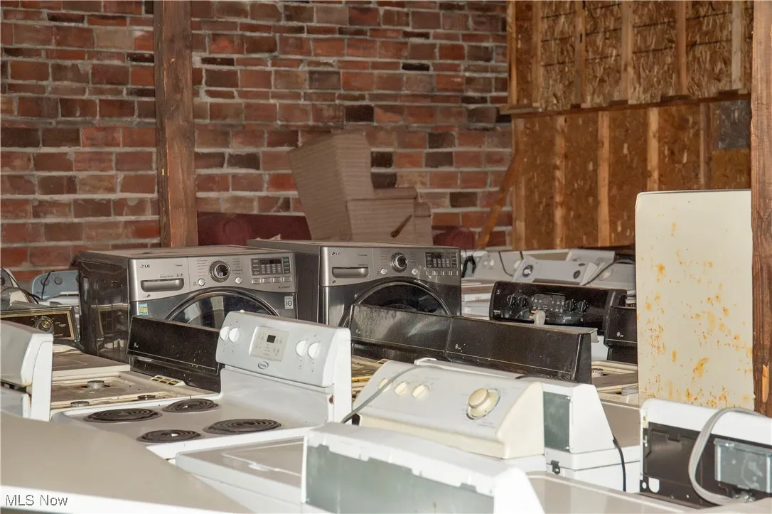 Laundry area featuring brick wall and washing machine and clothes dryer