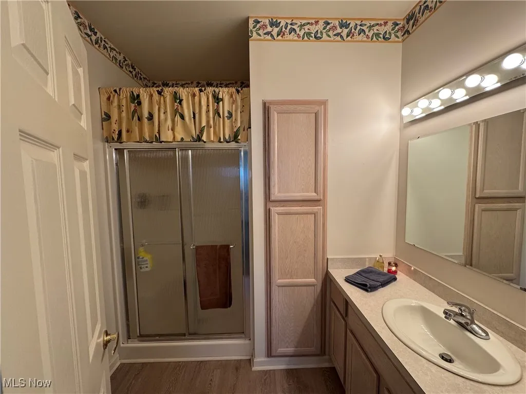 Bathroom with hardwood / wood-style flooring, vanity, and an enclosed shower