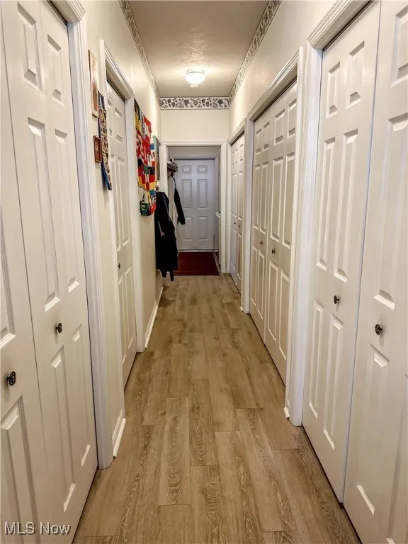Corridor featuring light hardwood / wood-style floors and a textured ceiling