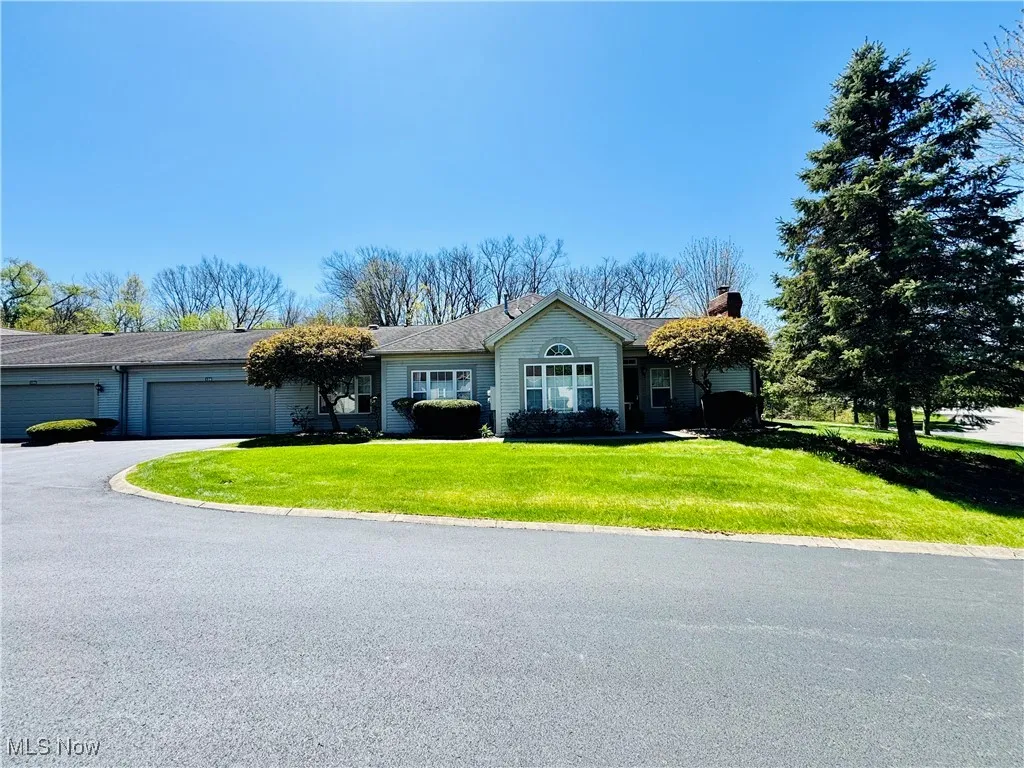Ranch-style home with a front yard, a garage, aphalt driveway, and a chimney