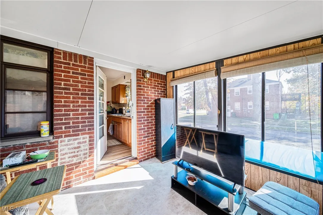 Three season room with vinyll tile flooring surrounded by windows.