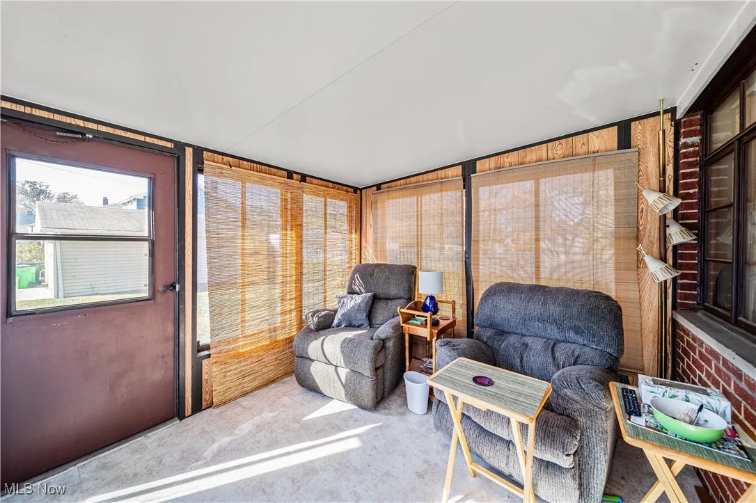 Three season room with vinyll tile flooring surrounded by windows.
