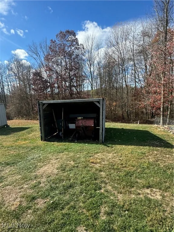 View of outdoor structure featuring a lawn and a carport