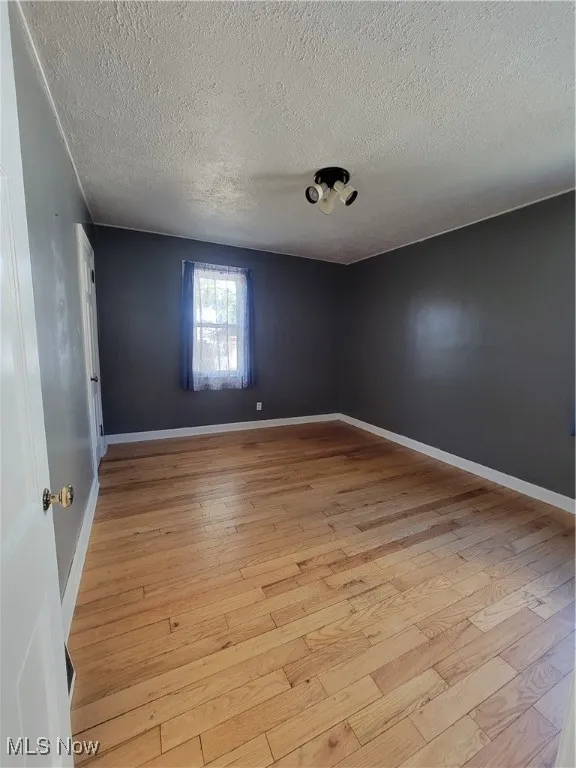 Unfurnished room with light hardwood / wood-style flooring and a textured ceiling