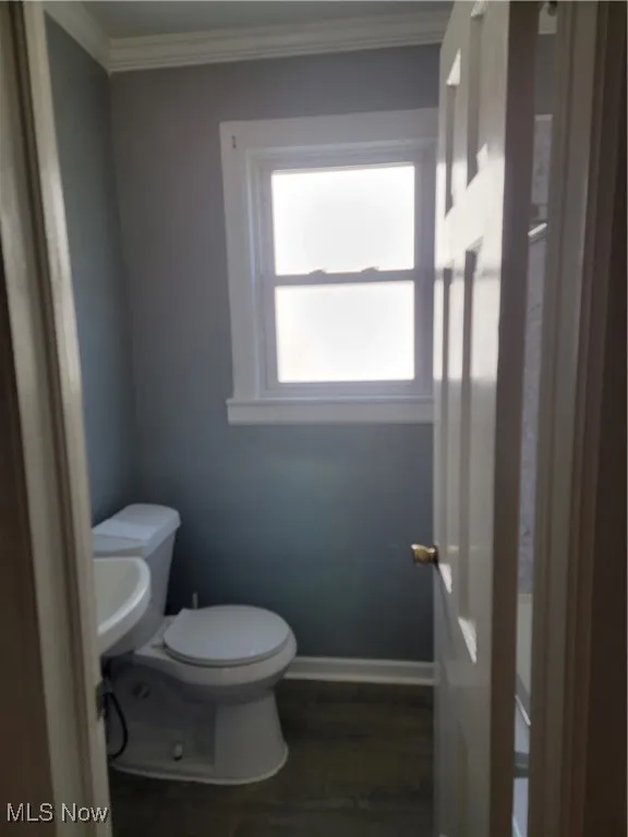 Bathroom featuring toilet, hardwood / wood-style flooring, and crown molding