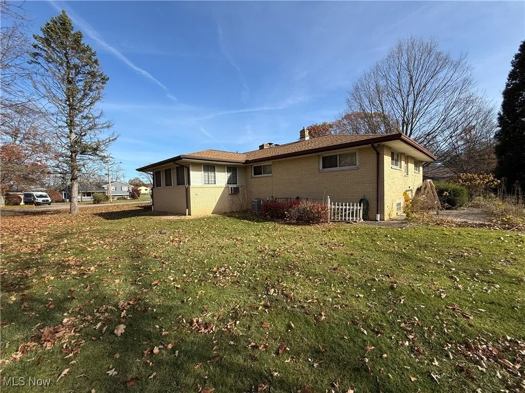 View of side of home featuring central air condition unit and a yard