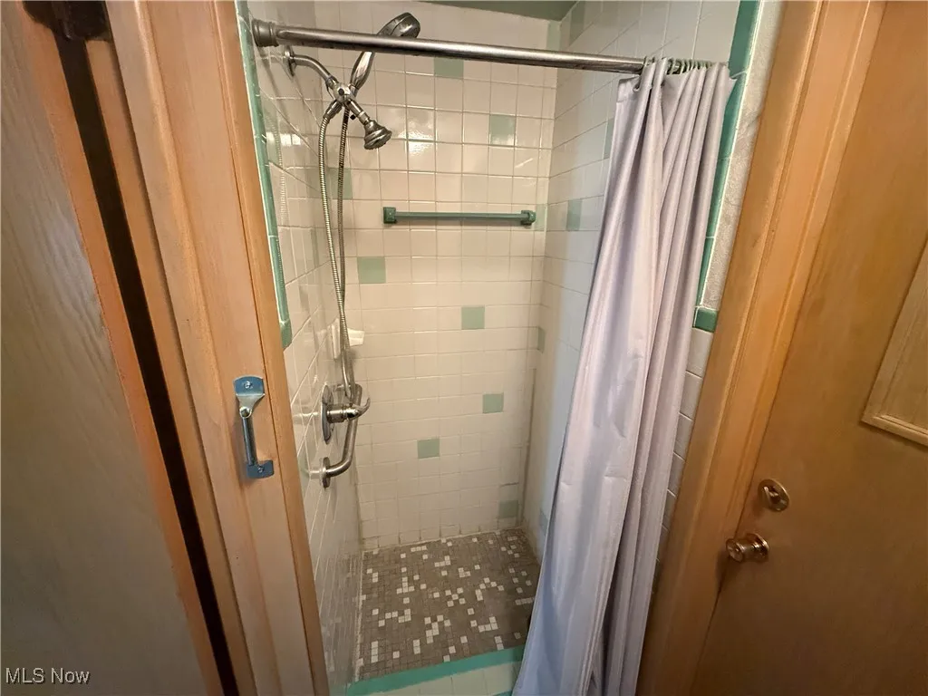 Bathroom with a shower with shower curtain and tile patterned floors