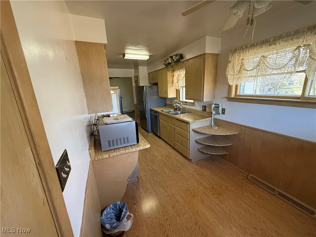 Kitchen featuring light wood-type flooring, appliances with stainless steel finishes, sink, and ceiling fan