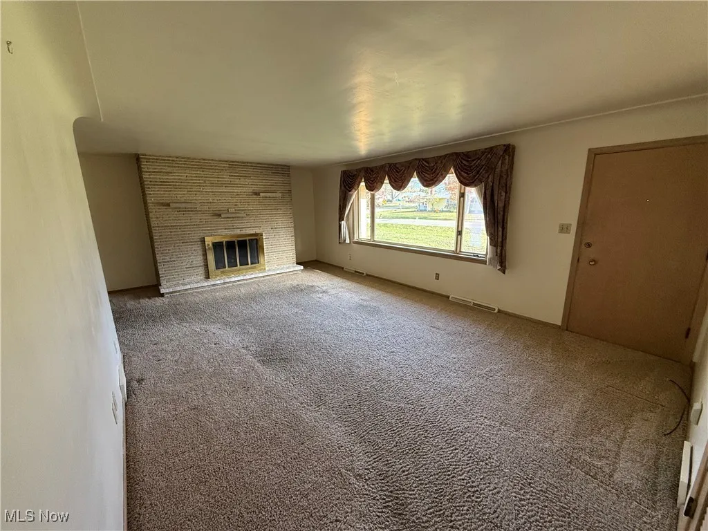 Unfurnished living room with a fireplace and carpet
