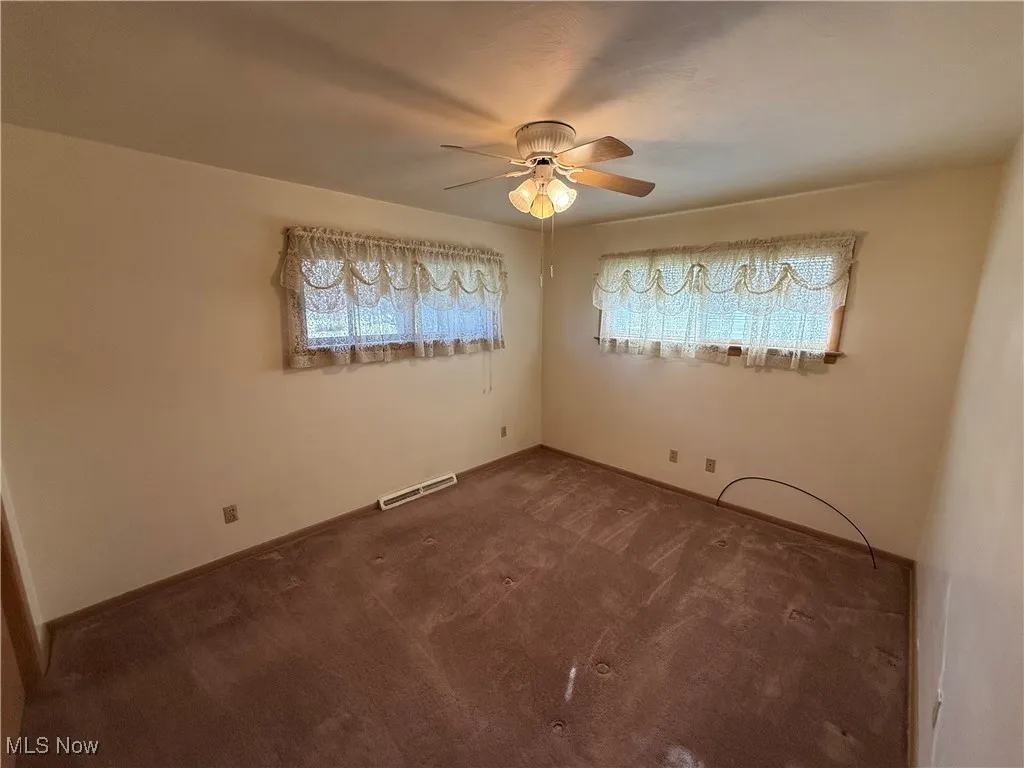 Carpeted spare room featuring ceiling fan