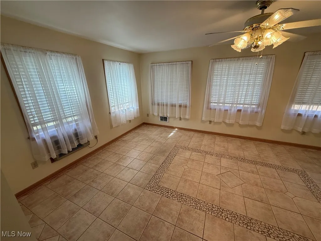 Unfurnished room featuring light tile patterned floors and ceiling fan