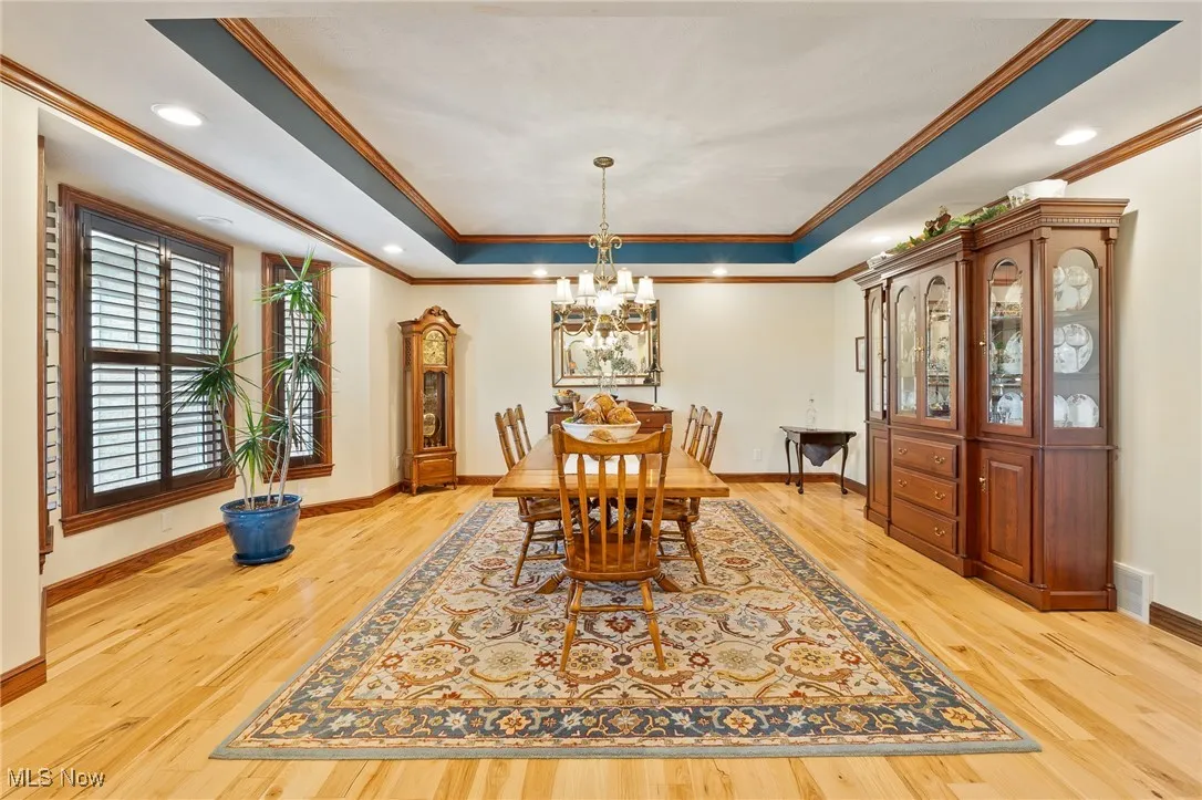 Dining room with ornamental molding, light hardwood / wood-style floors, and an inviting chandelier