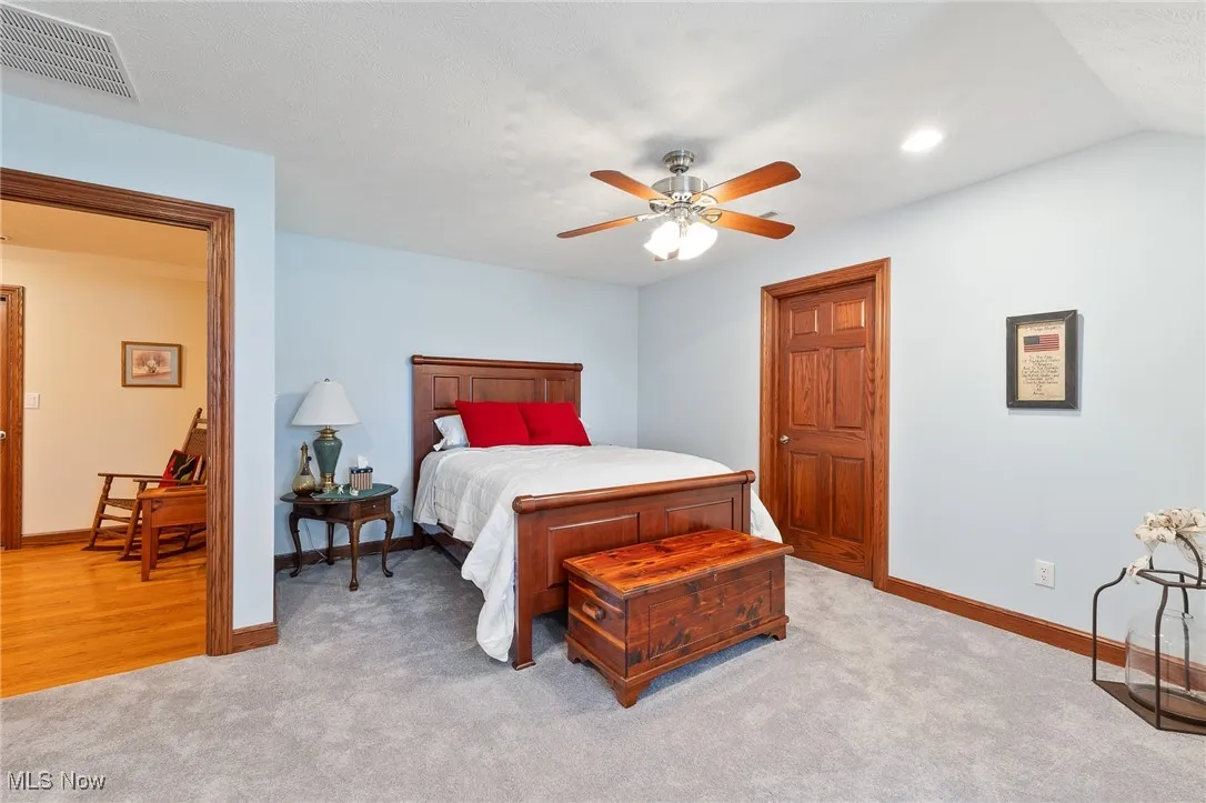 Bedroom featuring ceiling fan, lofted ceiling, and light carpet