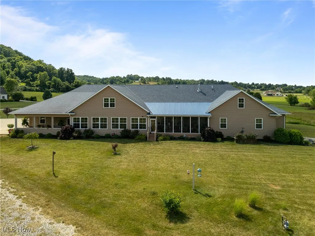 Back of house with a yard and a sunroom