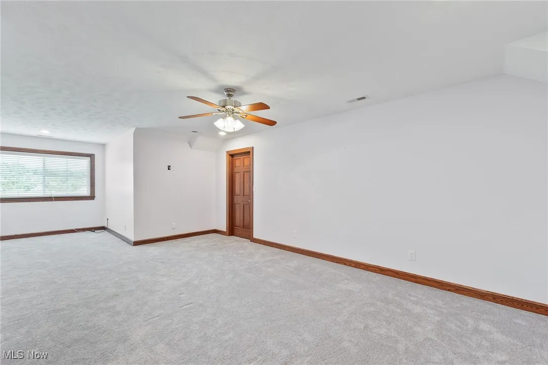 Carpeted spare room featuring ceiling fan and a textured ceiling