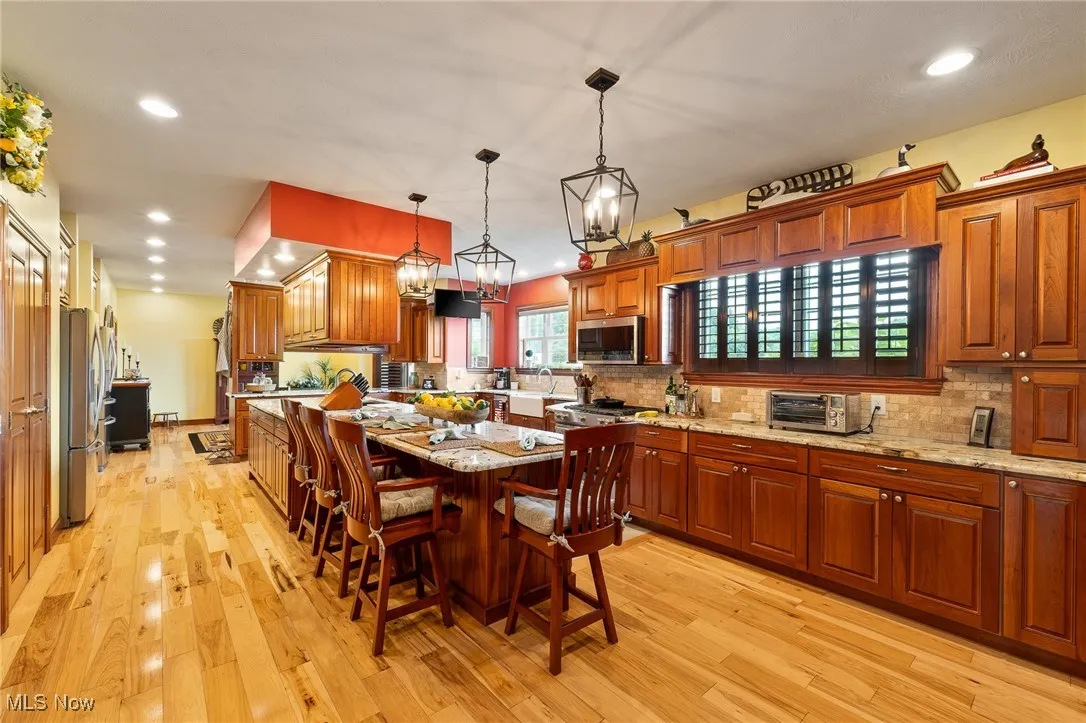 Kitchen with light hardwood / wood-style flooring, appliances with stainless steel finishes, a breakfast bar area, and an inviting chandelier