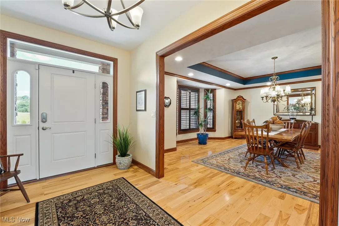 Entrance foyer featuring hardwood / wood-style flooring, an inviting chandelier, and ornamental molding