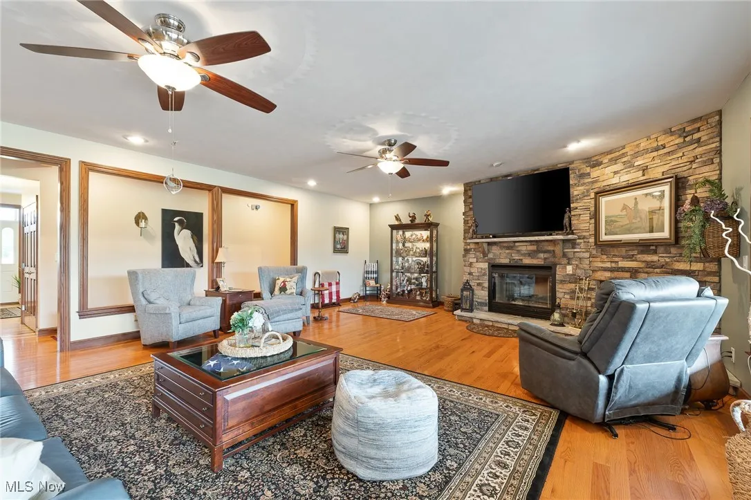 Living room featuring a fireplace, hardwood / wood-style flooring, and ceiling fan
