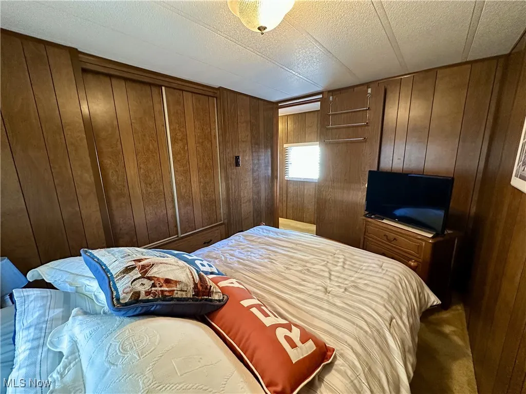 Carpeted bedroom featuring wood walls and a textured ceiling