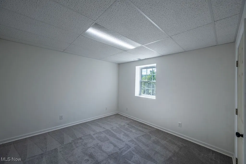 Unfurnished room with carpet flooring and a drop ceiling