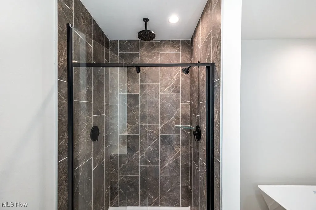Full bathroom featuring a marble finish shower and recessed lighting