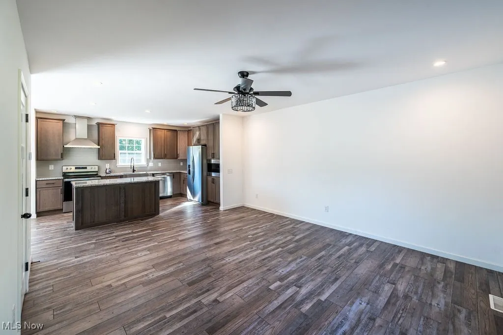 Kitchen with open floor plan, a center island, recessed lighting, appliances with stainless steel finishes, and dark wood finished floors