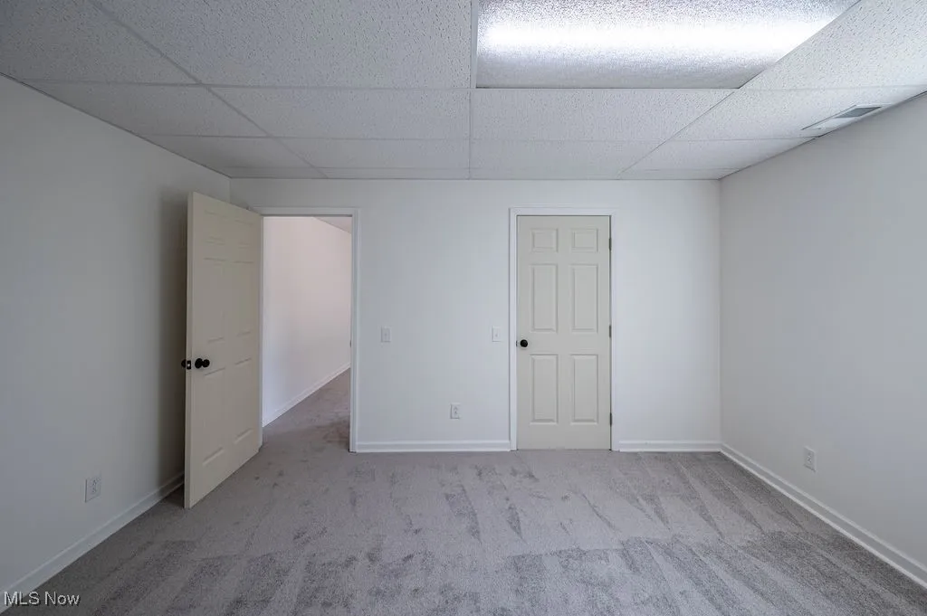 Unfurnished bedroom with light colored carpet and a drop ceiling
