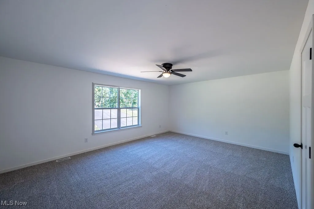 Empty room with carpet and a ceiling fan