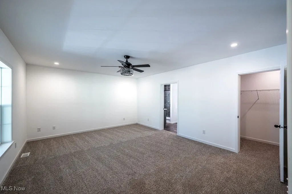 Unfurnished bedroom with recessed lighting, carpet flooring, a spacious closet, and a ceiling fan