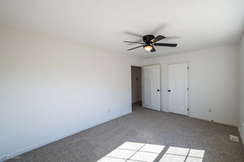 Unfurnished bedroom with light colored carpet, a closet, and a ceiling fan