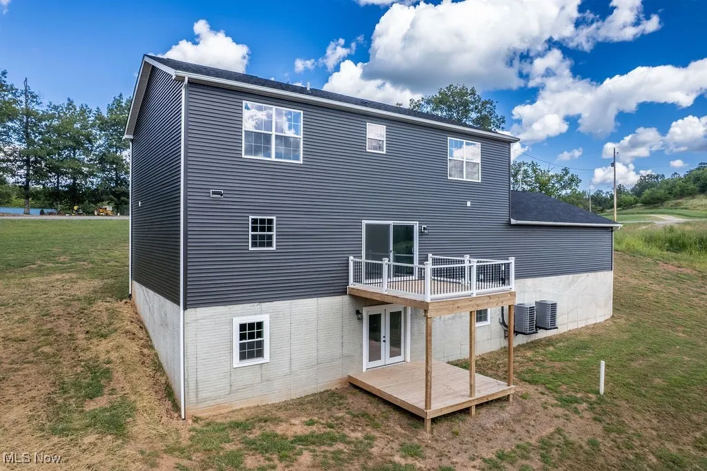 Back of house featuring french doors, a deck, and a lawn