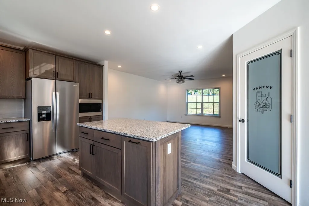 Kitchen with stainless steel appliances, recessed lighting, light stone counters, open floor plan, and a kitchen island