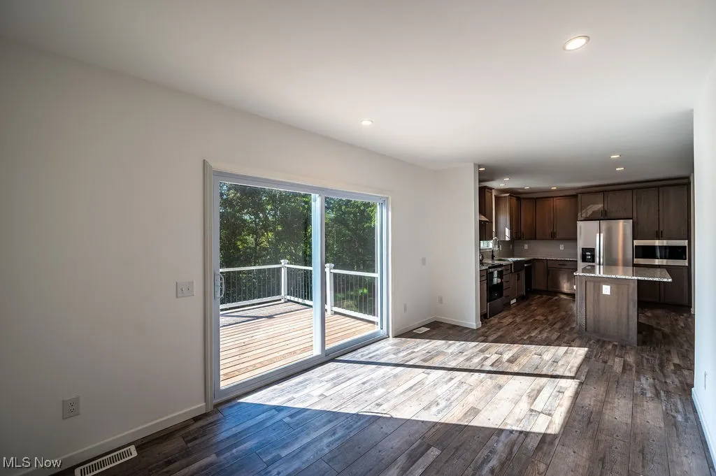 Kitchen featuring dark brown cabinets, dark wood-style flooring, a kitchen island, stainless steel appliances, and recessed lighting