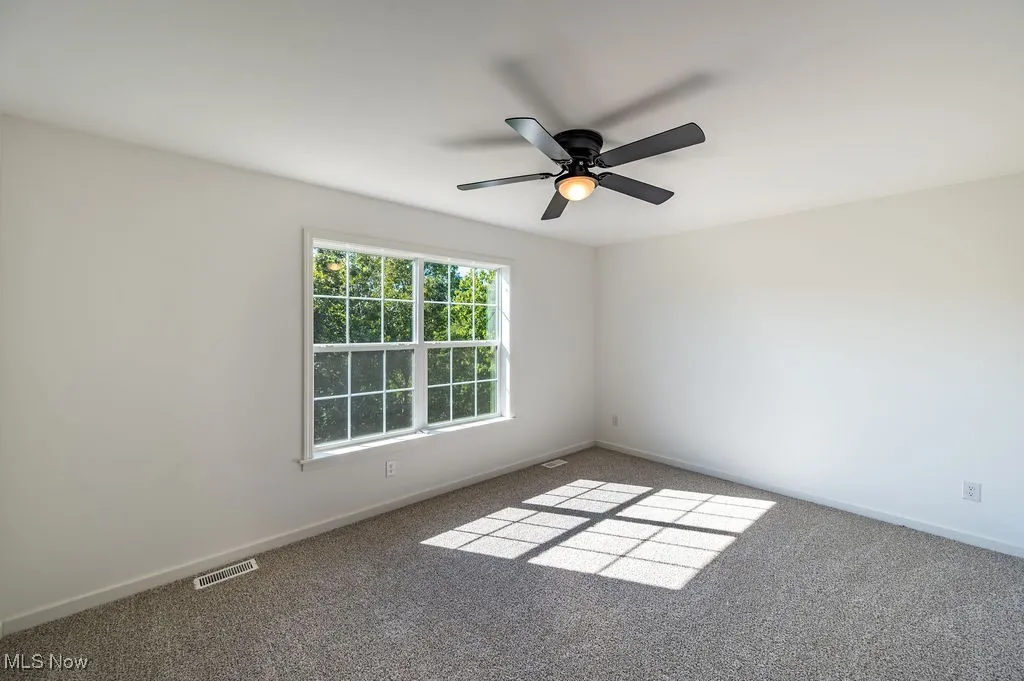 Empty room featuring carpet flooring and a ceiling fan