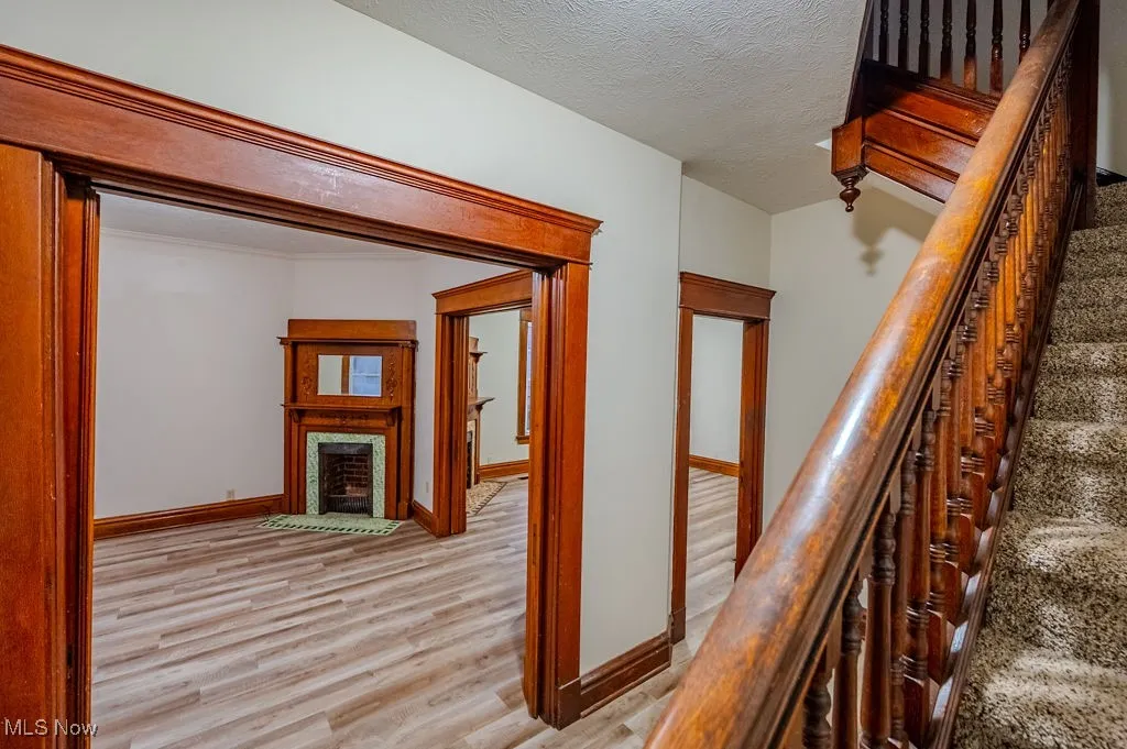 Corridor with a textured ceiling and light hardwood / wood-style flooring