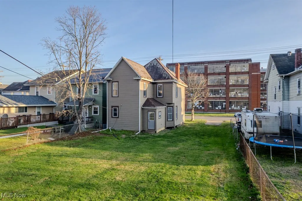 Back of property featuring a lawn and a trampoline