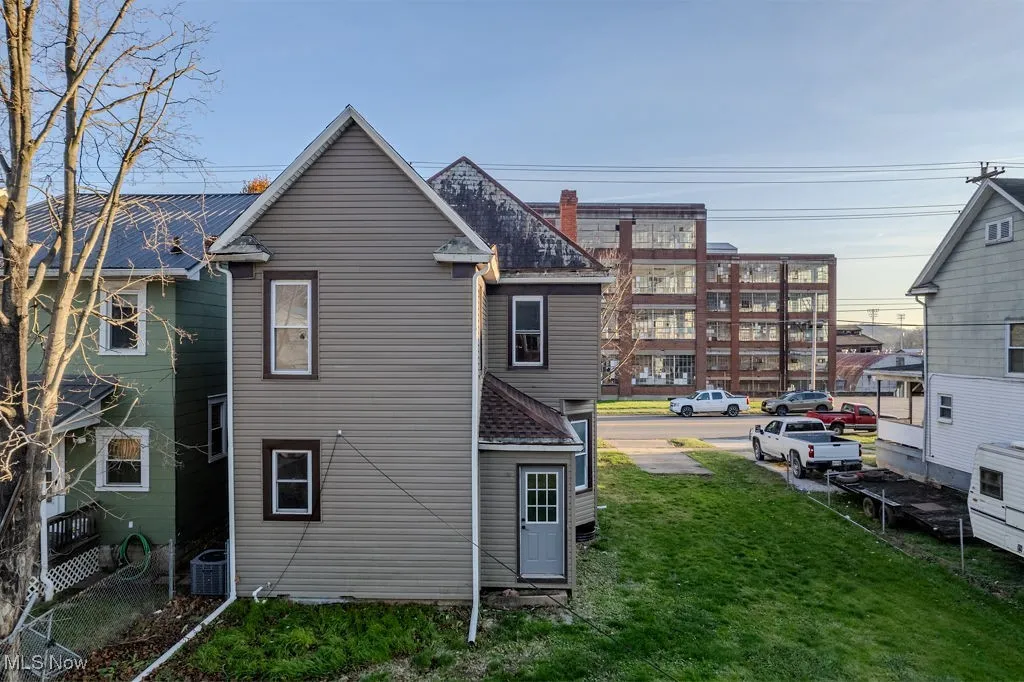 Back of house with a lawn and central AC unit